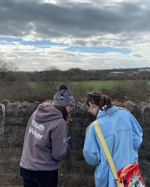 Back view of Two women in the countryside, looking at something like a map or a phone